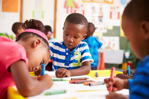 Photo of kids writing at a desk